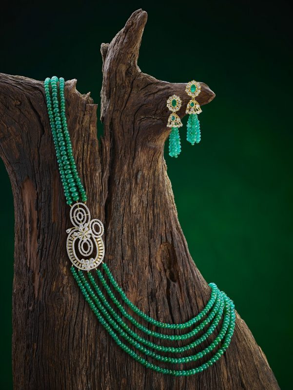 Colorful Mugappu necklace and earring set displayed on natural wood. Lovely example of Akshaya Tritiya fine jewellery.